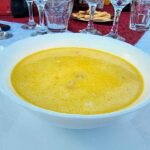 A yellow soup inside a deep, white plate