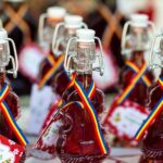 Small bottles in the shape of guitars filled with red sour cherry liquor. They have a ribbon around the necks with the three colours of the Romanian flag: red, yellow, and blue.