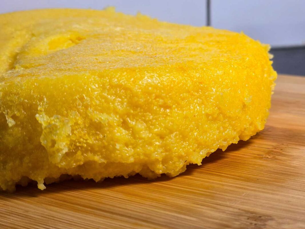 A close-up of the polenta, which is yellow, on a wooden board.